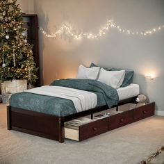 a bed with two drawers underneath it and a christmas tree in the background