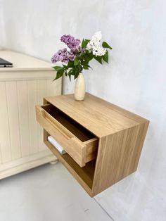 a vase with some flowers in it next to a wall mounted mailbox and desk