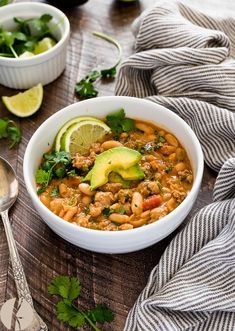 a white bowl filled with beans and avocado on top of a wooden table