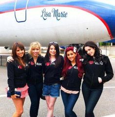 four girls standing in front of an airplane