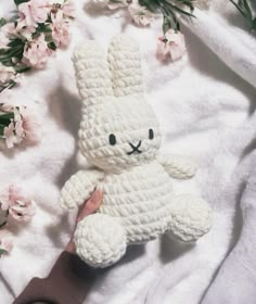 a crocheted white bunny is held by someone's hand