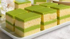 several pieces of green and yellow cake on a white plate with flowers in the background