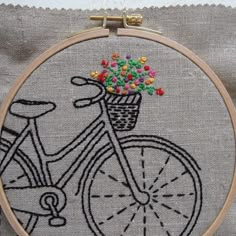 a close up of a embroidery on a piece of cloth with a bike and flowers