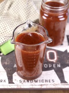 two jars filled with sauce sitting on top of a table