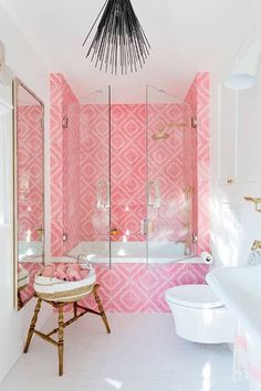 a bathroom with pink and white wallpaper, a chandelier over the bathtub