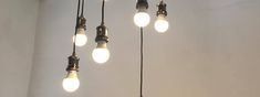 several light bulbs hanging from the ceiling in a room with white walls and flooring