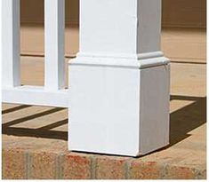 a white bench sitting on top of a sidewalk next to a brick wall and grass