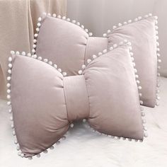 three pillows with white pom - poms on them