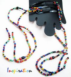 multicolored beaded necklace with black case on white surface next to small object