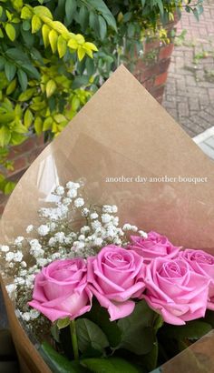 a bouquet of pink roses in a brown paper wrapped box with baby's breath