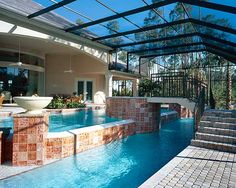 an indoor swimming pool with steps leading up to it and a glass roof over the pool