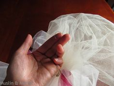 a person holding something in their hand on top of a white cloth with pink and white ribbons