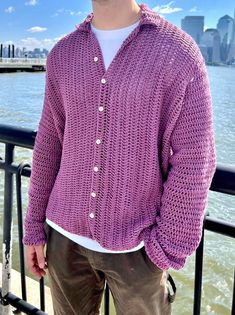 a man wearing a purple knitted cardigan by the water