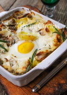 an egg and cheese casserole is in a white dish on a wooden table