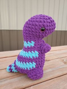 a purple stuffed animal sitting on top of a wooden table