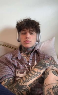 a man with headphones and tattoos laying in bed