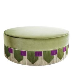 a round ottoman with purple and green designs on the top, sitting in front of a white background