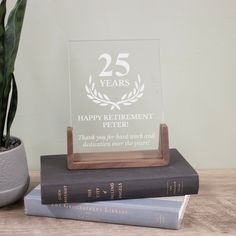 two books are stacked on top of each other next to a glass plaque that reads 25 years happy retirement peter