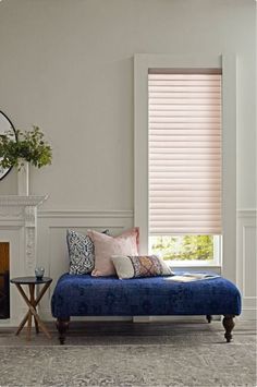 a living room with a blue couch and white fireplace in the corner next to a mirror