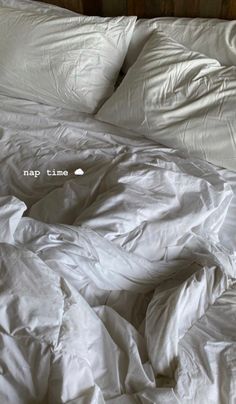 an unmade bed with white sheets and pillows