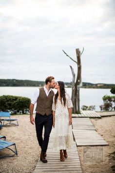 a man and woman walking down a wooden walkway