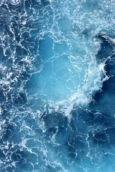 an aerial view of the ocean with blue water and foamy waves on it's surface