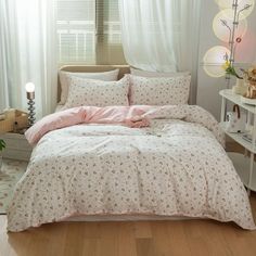 a bedroom with white curtains and pink bedding