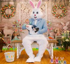 a man in bunny suit holding a baby while sitting on a bench with easter decorations around him