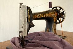 an old sewing machine sitting on top of a wooden table next to a purple blanket