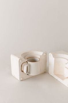 two pieces of white pottery sitting next to each other