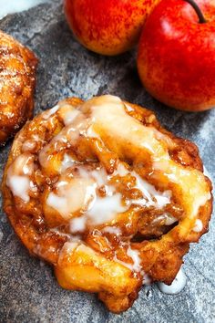 apple cinnamon rolls with icing and two apples on the side, one is half eaten