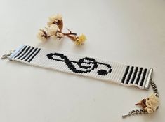 a white bracelet with a black and white bead design on it, next to a flower