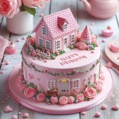 a pink birthday cake decorated with roses and a house