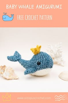 a crocheted baby whale amigurmi is sitting next to some seashells