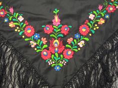 an embroidered black shawl with flowers and fringes