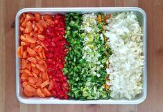 chopped vegetables are in a white dish on a wooden surface, including carrots, onions and celery