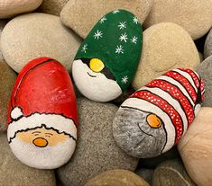 three painted rocks with santa hats on them