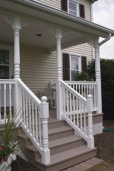 a white porch with steps leading up to the front door and side of a house