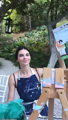 a woman is sitting in front of an easel