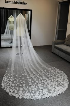 a wedding dress is displayed in front of a mannequin's dummy with flowers on the floor