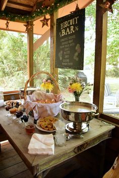 a wooden table topped with lots of food next to a sign that says biscuit bar