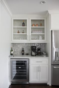 a kitchen with white cabinets and stainless steel appliances, including a wine cooler in the corner