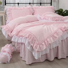 a bed with pink sheets and ruffled trims on the bottom, along with matching pillows