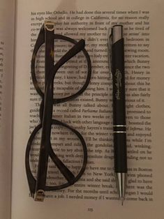 an open book with glasses, pen and eyeglasses on it