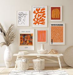 a white table topped with vases filled with flowers next to pictures on the wall