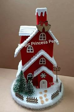 a red and white christmas house with snow on the roof is shown in front of a brown background