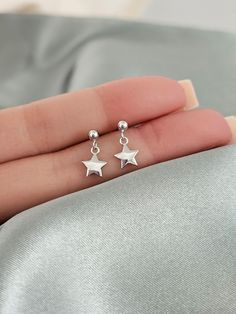 These sterling silver star dangle earrings are perfect for anyone who loves minimalistic style. An ideal gift for both kids and adults of all ages. They are made from hypoallergenic nickel free sterling silver to ensure that even those with sensitive skin can wear them without any irritation. Finish: platinum plated over sterling silver. Size: 3mm ball studs, 7mm star charms. Post size: 21 gauge, 11mm long Sold as a PAIR of two earrings. Comes with gift box ready for gift giving. Sterling silver Silver Sterling Earrings, Minimalist Star Charm Earrings As Gift, Tiny Gift Ideas, Cute Silver Earrings, Sterling Silver Star Earrings, Simple Silver Earrings, Star Dangle Earrings, Silver Butterfly Earrings, Neck Pieces Jewelry