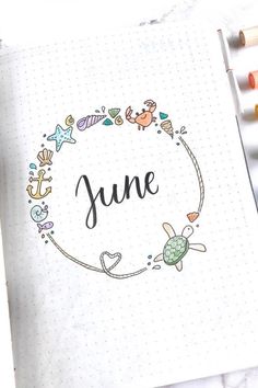 an open notebook with the word june written in it and some crayons next to it