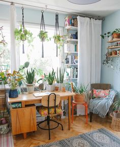 a room filled with lots of potted plants next to a wooden desk and chair