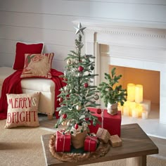 a christmas tree with presents under it in front of a fire place and pillows on the floor